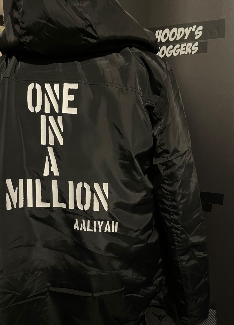 Zwarte jas met witte letters One in a Million en een naam